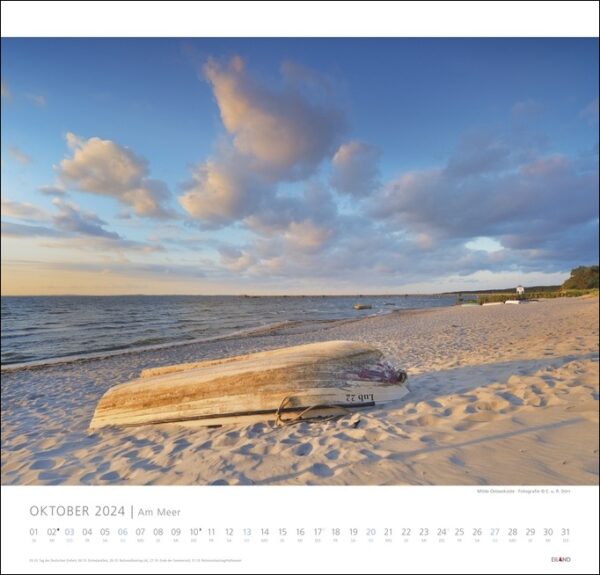 Ein Kalender mit einem Holzboot am Strand vor der malerischen Kulisse von „Am Meer 2024“.