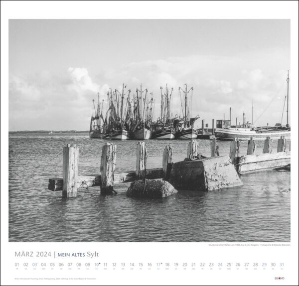 Ein Schwarz-Weiß-Foto von MEIN ALTES Sylt - Bleicke Bleicken 2024, einem im Wasser angedockten Boot.