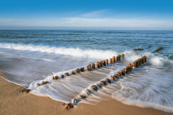 Küste - Holzpfahlbuhnen mit Holzpfahlbuhnen am Strand.