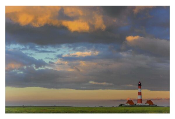 Ein Leuchtturm im Küstenland - Wolkenmarmor über Westerheversand unter bewölktem Himmel.