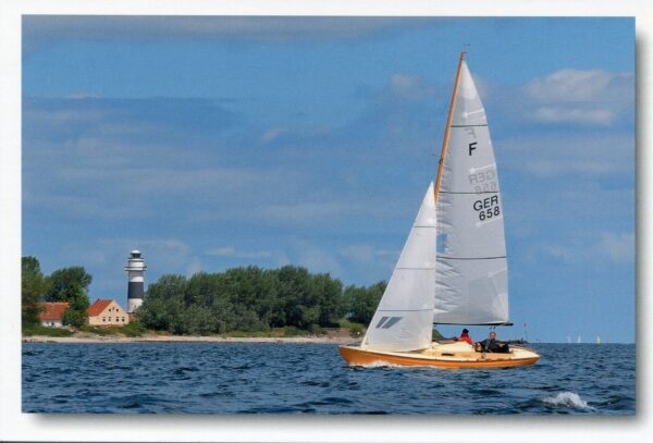 Ein Segelboot auf der Waterkant mit „Waterkant – Der Leuchtturm Bülk bei Kiel“ im Hintergrund.