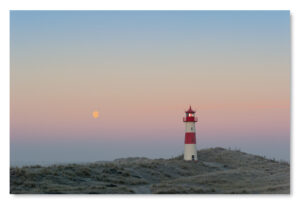 Ein Leuchtturm auf einer Sanddüne mit dem Produktnamen „Sylt Impressionen – Der Mond ist aufgegangen über dem ‚Ellenbogen‘“ am Himmel bei Sylt Impressionen.