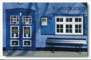 Eine blaue Tür und Tor - Ahrenshoop / Mecklenburg-Vorpommern mit einer Bank davor in Ahrenshoop, Mecklenburg-Vorpommern.