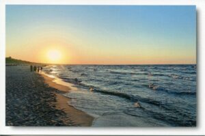 Die Sonne geht über Usedom - Meine Insel - Am Strand von Zinnowitz unter und Menschen laufen im Sand.