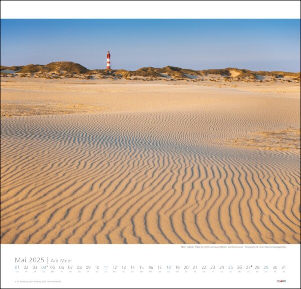 Eine Kalenderseite für Am Meer 2025 mit einem Sandstrand mit welliger Textur, der zu windgepeitschten Dünen führt. In der Ferne steht ein rot-weiß gestreifter Leuchtturm im Hintergrund.