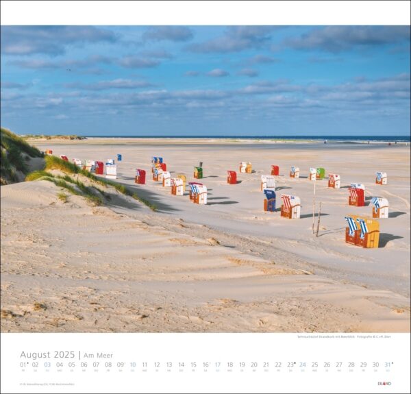 Eine Strandszene mit einer Reihe bunt gestreifter Strandstühle mit Blick auf das Meer. Der Strand ist breit und hat feinen, hellen Sand unter einem klaren blauen Himmel. Eine Am Meer 2025-Überlagerung für August 2025 dominiert den Kalender.