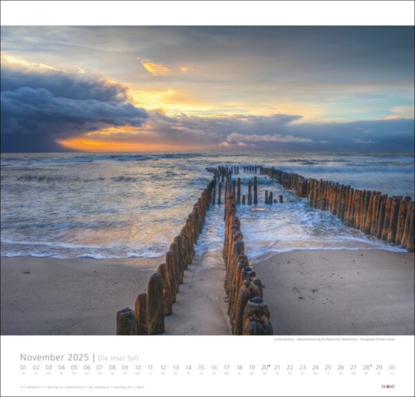 Ein Kalender für die Insel Sylt 2025 mit einem Foto eines hölzernen Wellenbrechers, der sich bei Sonnenuntergang in ein stürmisches Meer erstreckt, mit dunklen Wolken und einem orangefarbenen Schimmer am Horizont, aufgenommen auf der Insel.