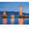 Eine Kalenderseite für November 2025 mit einer Abenddämmerungsszene eines Hafens mit einem historischen Leuchtturm und einer Statue auf den Piers sowie einem vorbeifahrenden Boot. Textdetails zu „Faszination Leuchttürme – An den Grenzen der Landschaft 2025“