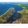 Luftaufnahme einer Küstenstadt in Schleswig-Holstein, Deutschland, mit einem Schleswig-Holstein-Kalender 2025. Das Bild zeigt einen Fluss, der ins Meer mündet, mit einem Yachthafen.