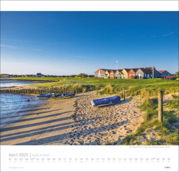 Eine Kalenderseite für Inseln & Meer 2025 mit einer ruhigen Strandszene mit einem umgekippten Boot im Vordergrund, einem ruhigen Meer links und einer Reihe bunter Häuser unter einem klaren blauen Himmel.