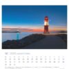 Das Bild ist eine Leuchttürme - PostkartenKalender 2025-Seite für Dezember, auf der ein Leuchtturm in der Abenddämmerung abgebildet ist. Lichtstreifen vorbeifahrender Fahrzeuge erhellen die Szene. Der Leuchtturm ist rot und weiß.