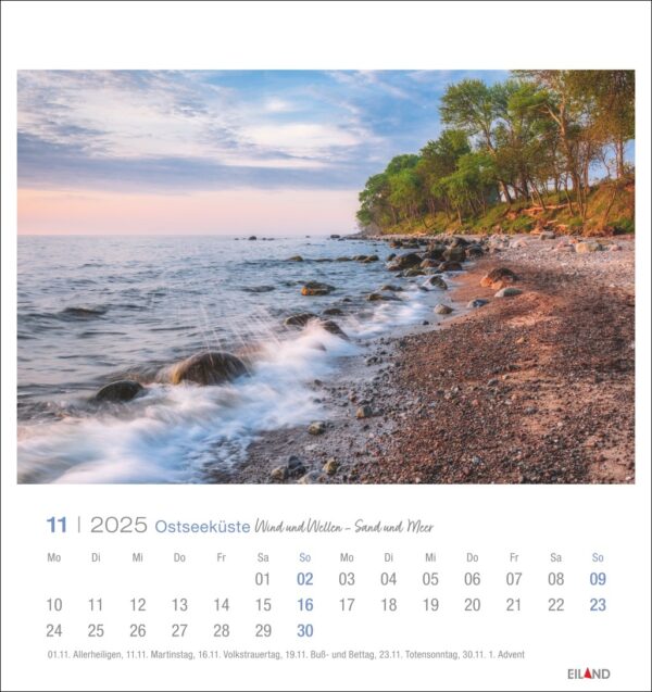 Eine Ostseeküste - PostkartenKalender 2025 Seite für November mit einer ruhigen Strandszene bei Sonnenaufgang, mit sanften Wellen, die auf das felsige Ufer treffen, unter einem zartrosa und blauen Himmel. Das Kalenderraster enthält