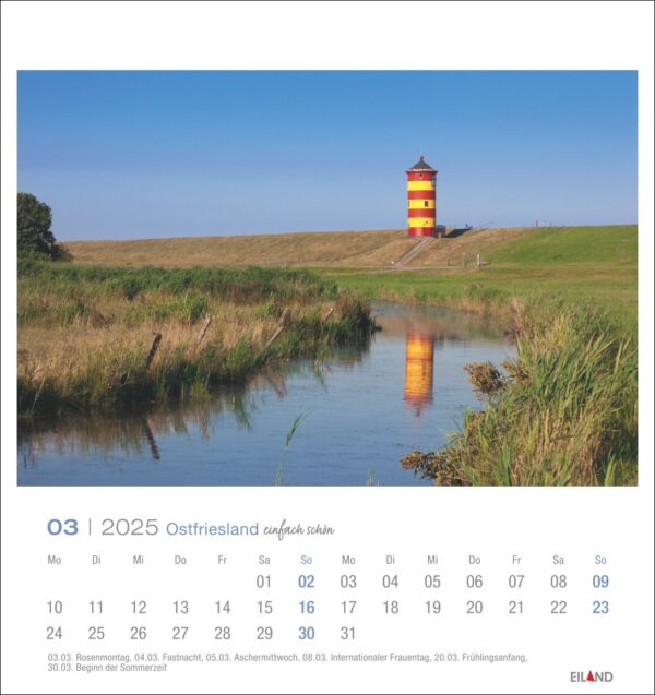 Eine Ostfriesland einfach schön - PostkartenKalender 2025 Seite für März mit einem Landschaftsfoto eines wunderschönen leuchtend roten und gelben Leuchtturms in Ostfriesland neben einem reflektierenden Fluss, umgeben von grünen Grashügeln unter einem