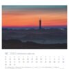 Eine Seite des Ostfriesland einfach schön - PostkartenKalender 2025 für Dezember mit einer ruhigen Landschaft in der Abenddämmerung mit einem hohen Leuchtturm in der Mitte, umgeben von nebligen Hügeln unter einem leuchtend rosa und blauen Himmel.