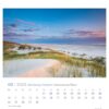 Eine Seite des Schleswig-Holstein - PostkartenKalenders 2025 für Februar mit einer ruhigen Strandszene bei Sonnenuntergang mit pastellfarbenem Himmel, sanften Wellen und Sanddünen, die mit spärlicher Vegetation bedeckt sind. Tage und Daten sind in einem Kalenderformat aufgeführt.