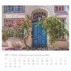 Eine Seite des Schleswig-Holstein - PostkartenKalenders 2025 für Juli mit einem charmanten Haus mit einer leuchtend blauen Tür und Fenstern, geschmückt mit üppigen roten Rosen, die um den Eingang ranken. Die Hauswände sind cremefarben. Der Kalender