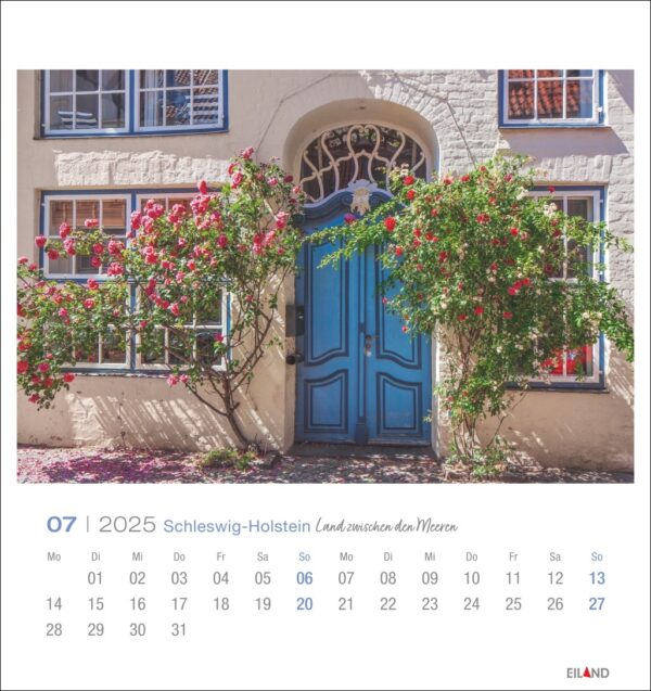 Eine Seite des Schleswig-Holstein - PostkartenKalenders 2025 für Juli mit einem charmanten Haus mit einer leuchtend blauen Tür und Fenstern, geschmückt mit üppigen roten Rosen, die um den Eingang ranken. Die Hauswände sind cremefarben. Der Kalender