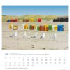 Eine Seite des Schleswig-Holstein - PostkartenKalenders 2025 für August 2025 zeigt einen ruhigen Strand mit Reihen bunter Strandkörbe in Gelb, Rot, Blau und Grün. Im Vordergrund mehrere Möwen.
