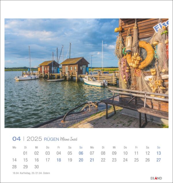 Eine Seite des Rügen - PostkartenKalenders 2025 für April mit einer ruhigen Hafenszene auf der Insel Rügen, Deutschland. Kleine Boote liegen an einem Holzsteg festgemacht, mit einem malerischen Gebäude geschmückt mit