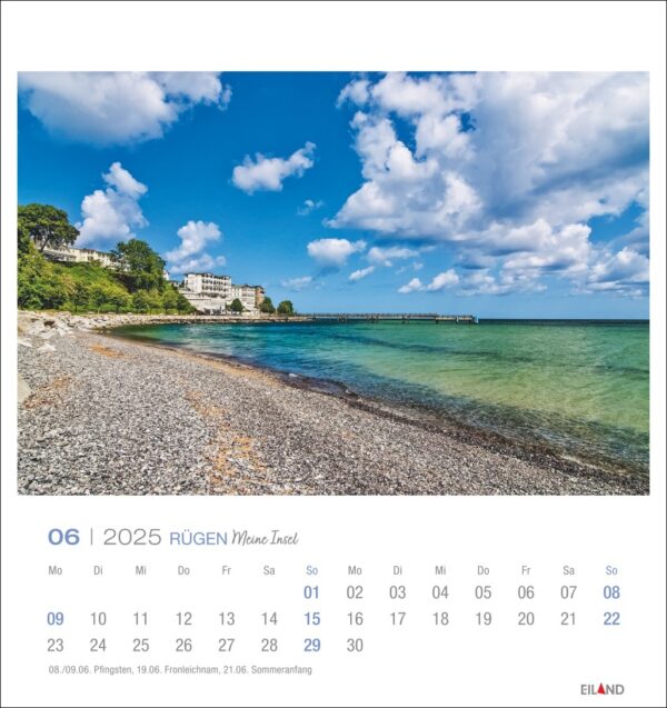 Eine Rügen - PostkartenKalender 2025 Seite für Juni mit einer ruhigen Strandszene auf der Insel Rügen, Deutschland, mit klarem türkisfarbenem Wasser, Kieselstrand und entfernten Gebäuden unter einem blauen