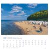 Eine Kalenderseite für August 2025 aus dem Rügen - PostkartenKalender 2025 zeigt eine Strandszene auf der Insel Rügen, Deutschland. Menschen sonnen sich und schwimmen in der Nähe von weißen Strandkörben auf