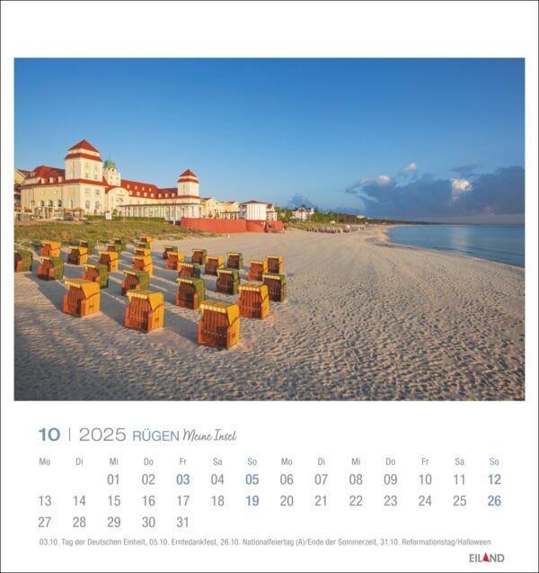 Eine Rügen - PostkartenKalender 2025 Seite für Oktober mit einem Foto eines ruhigen Strandes auf Rügen, Deutschland bei Sonnenaufgang. Reihen von Strandkörben mit Überdachung blicken auf das Meer, mit einem historischen Hotel