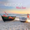 Ein Werbebild für Usedom – PostkartenKalender 2025 mit dem Titel „meine Insel“, das zwei Boote mit bunten Paddeln auf einem Sandstrand vor einem Sonnenuntergangshimmel zeigt, mit „2025“ am unteren Rand.