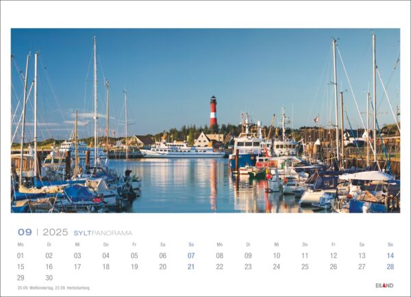 Eine Kalenderseite für das Sylt Panorama 2025 für September, die ein ruhiges Sylt-Panorama mit festgemachten Segelbooten, Fischerbooten und einem markanten roten Leuchtturm unter einem klaren blauen Himmel zeigt. Das Kalenderraster
