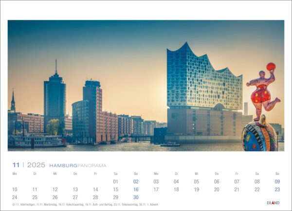 Eine Kalenderseite des Hamburg Panorama 2025 für November mit einem ruhigen Panorama von Hamburg, Deutschland, mit modernen Gebäuden wie der Elbphilharmonie und einer farbenfrohen Skulptur eines Clowns auf einem Einrad.