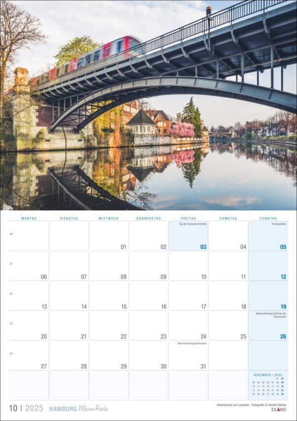 Eine Kalenderseite für Hamburg …meine Perle 2025 mit dem Bild einer Brücke in Hamburg, Deutschland, bekannt als „Hamburg, meine Perle“, mit einem darüberfahrenden Zug und ruhigem Wasser darunter, in dem sich die