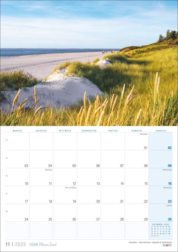 Eine Kalenderseite für Föhr ...meine Insel 2025 mit einer ruhigen Strandszene auf der Insel Föhr mit hohem Gras im Vordergrund und einem klaren blauen Himmel darüber. Der Kalender ist in deutscher Sprache, mit