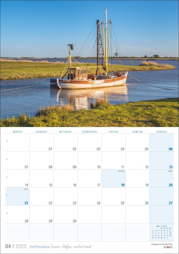 Ein Kalenderblatt mit Ostfriesland 2025 und einem Foto eines traditionellen Segelboots auf ruhigem Wasser in der Nähe von grasbewachsenen Ufern unter einem klaren blauen Himmel in Ostfriesland. Wochentage auf Deutsch