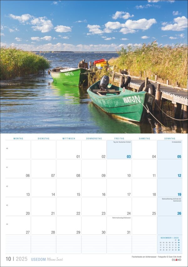 Dieses Bild zeigt eine Kalenderseite für Oktober 2025 mit einer ruhigen Seeszene auf Usedom …meine Insel 2025. Zwei kleine, bunte Boote mit den Aufschriften WAT-31 und WAT-37 liegen in der Nähe vor Anker.
