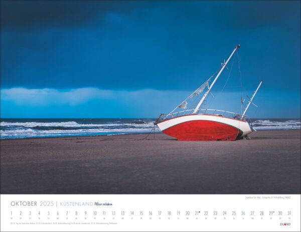 Eine Kalenderseite für den Oktober „Küstenland – Meer erleben 2025“ mit dem Foto eines gekenterten Segelboots mit rotem Rumpf an einem Sandstrand unter stürmischem Himmel. Das Meer ist voller Wellen.