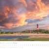 Ein Kalender für Dezember 2025 von „Küstenland – Meer erleben 2025“, der einen malerischen Sonnenuntergang über einer Küstenlandschaft mit einem hohen rot-weißen Leuchtturm, einem malerischen Dorf und einer dramatischen …