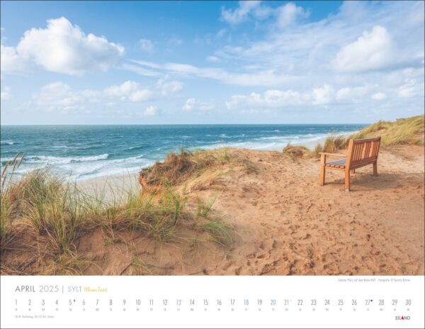 Ein malerischer Sylt-Meine-Insel-Kalender 2025 mit einer ruhigen Sylter Strandszene. Eine einsame Holzbank blickt auf das Meer, umgeben von Sanddünen und grünem Gras unter einem klaren blauen Himmel mit flauschigen Wolken.