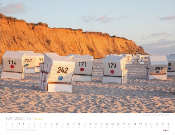 Ein Kalenderbild für Juni von Sylt – Meine Insel 2025 mit einem ruhigen Strand auf Sylt mit gleichmäßig verteilten weißen Strandkörben, die unterschiedlich nummeriert sind. Das Sandufer und eine Lehmklippe sind beleuchtet.