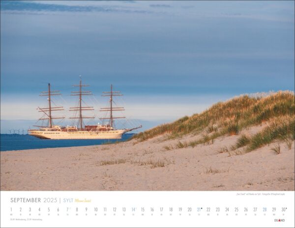 Ein Kalender für Sylt – Meine Insel 2025 mit einem großen Segelschiff mit drei Masten, das unter einem klaren Himmel in der Nähe des Sylter Sandstrandes mit Dünen und spärlichem Gras vor Anker liegt.