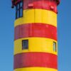 LongEiland - Kalender 2025 mit einem lebendigen Bild eines rot-gelb gestreiften Leuchtturms vor einem klaren blauen Himmel, der sich in Deutschland befindet, wie die Karte und die Flagge im unteren Abschnitt zeigen.