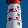 Ein vertikales Poster, das den LongEiland - Kalender 2025 vor einem Himmelshintergrund zeigt. Es zeigt einen großen weißen Leuchtturm mit roten Verzierungen und Streifen namens „Saint Mathieu“ vor einem blauen