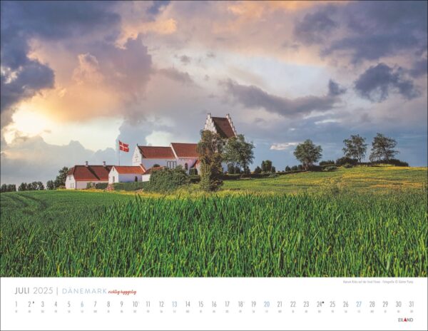 Ein DÄNEMARK – richtig hyggelig-Kalender für 2025 mit einer ruhigen Landschaft mit einem grünen Weizenfeld im Vordergrund, einem traditionellen dänischen Bauernhaus mit einer rot-weißen Flagge unter einem dramatischen Himmel bei Sonnenuntergang.