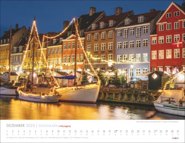 Ein DÄNEMARK - richtig hyggelig-Kalender 2025 mit einer Nachtszene in Nyhavn, Kopenhagen, mit farbenfrohen Gebäuden und dekorierten Segelbooten, die sich im Wasser spiegeln. Der Text weist darauf hin, dass der Kalender in Dänemark liegt.