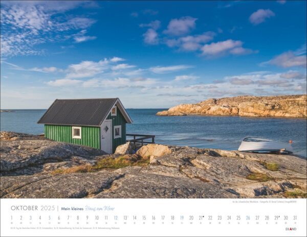Eine Kalenderseite für „Mein kleines Haus am Meer“ 2025 zeigt das Bild eines einsamen „Mein kleines Haus“ mit grünem Dach an einem ruhigen Meer, mit Felsen im Vordergrund und einem Boot auf der Seite.