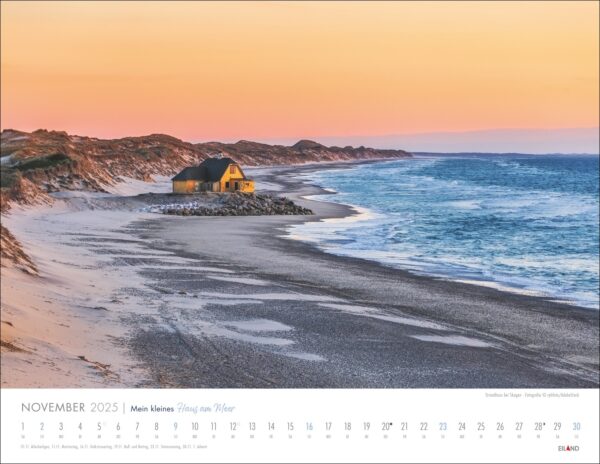 Eine Kalenderseite von „Mein kleines Haus am Meer“ für November 2025, die eine heitere Dämmerungsszene eines einsamen kleinen Hauses an einem Strand mit felsiger Küstenlinie, sanften Wellen und entfernten Dünen unter einem pastellfarbenen Himmel zeigt.