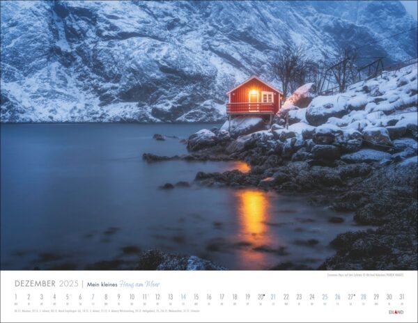 Eine Winterlandschaft mit einem warm beleuchteten „Mein kleines Haus am Meer 2025“ an einem verschneiten See, der einen Kontrast zu den umliegenden dunklen, schneebedeckten Bergen bildet. Die Spiegelung der Hütte leuchtet im stillen Wasser unter einem Abendhimmel.