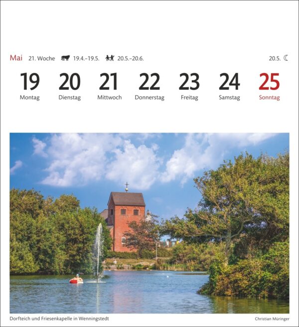 Eine Kalenderseite mit den Daten vom 19. bis 25. Mai, wobei Sonntag, der 25. Mai, rot hervorgehoben ist. Das Bild oben zeigt eine ländliche Szene mit einer Kirche an einem See mit einem Brunnen, einem Boot in der Nähe und umgebendem Grün.