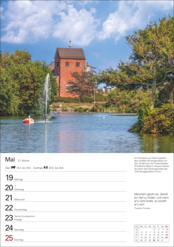 Eine malerische Kalenderseite für Mai, die einen ruhigen Teich mit einem Springbrunnen zeigt, flankiert von üppigem Grün und einer großen roten Backsteinkirche mit einem Kreuz auf der Spitze unter einem blauen Himmel. Daten und Text in Deutsch nehmen die untere Hälfte ein.