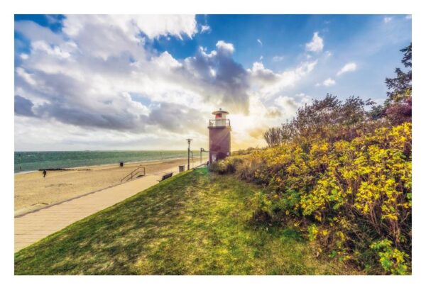 Eine malerische Küstenszene mit einem kleinen Leuchtturm auf einem grasbewachsenen Hügel, beleuchtet vom warmen Schein der untergehenden Sonne auf der Insel FÖHR...meine Insel. Üppiges Grün und gelbe Blumen sind in