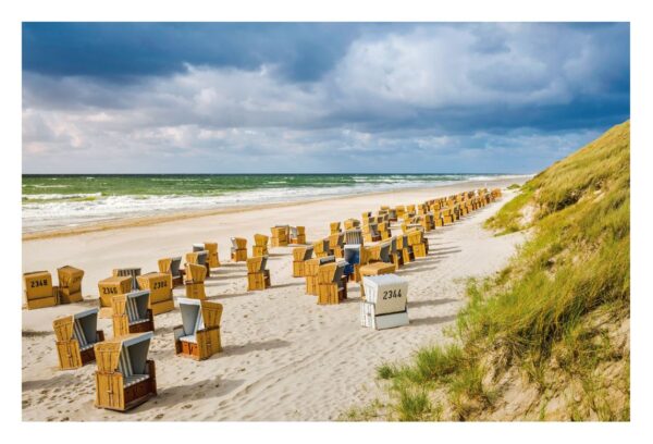 Ein windgepeitschter Strand auf SYLT ...meine Insel mit Reihen von Korbstühlen mit Überdachung, die auf das Meer blicken, unter einem bewölkten Himmel. Sanddünen mit grünem Gras sind auf der linken Seite sichtbar und verleihen dem Ganzen einen